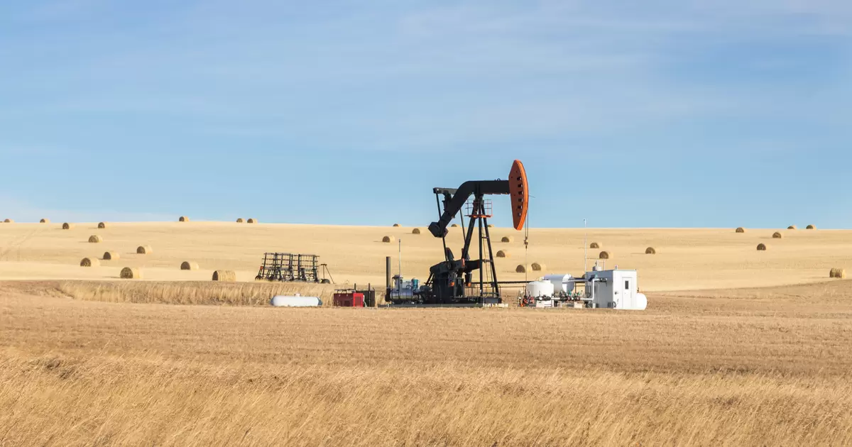 An oil pump jack in a farm field in Alberta, Canada.