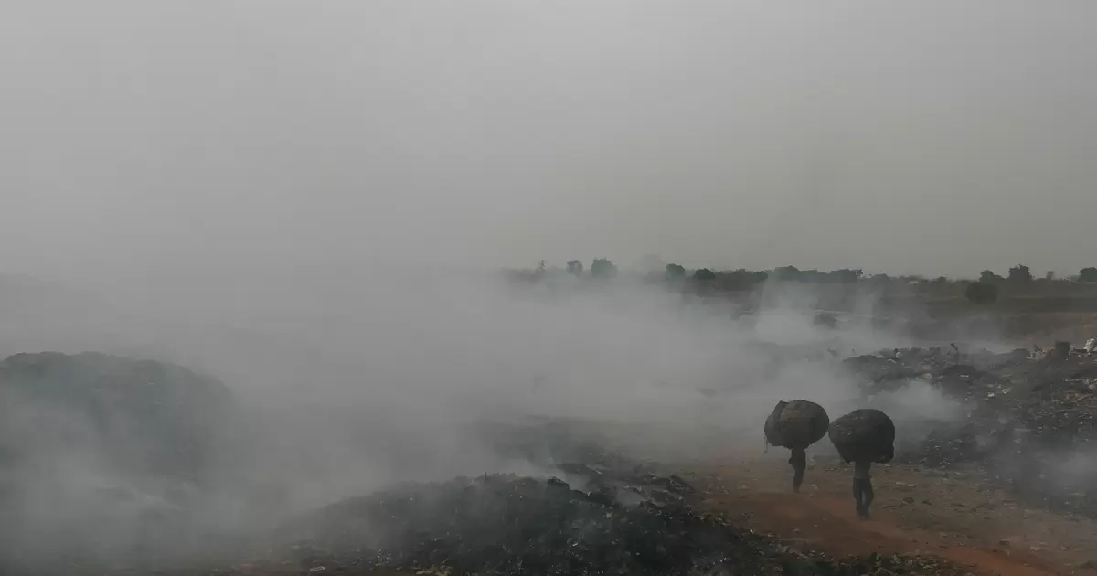 Scavengers walk through burning trash, Abuja, Nigeria. Poorly managed waste dumps are sources of methane and black carbon. 